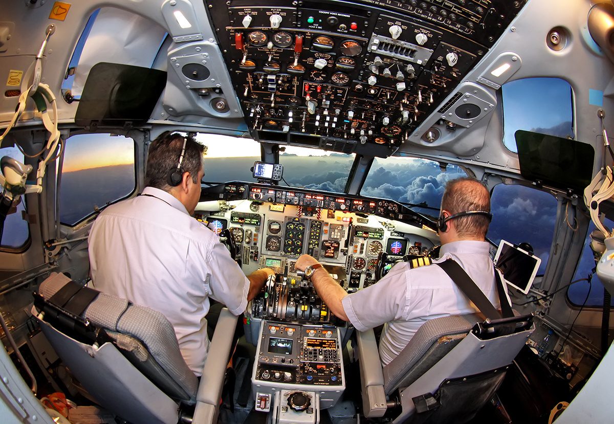 The flight deck of a McDonnell Douglas MD-83 in flight, with two pilots at the controls and the centre pedestal between their seats.