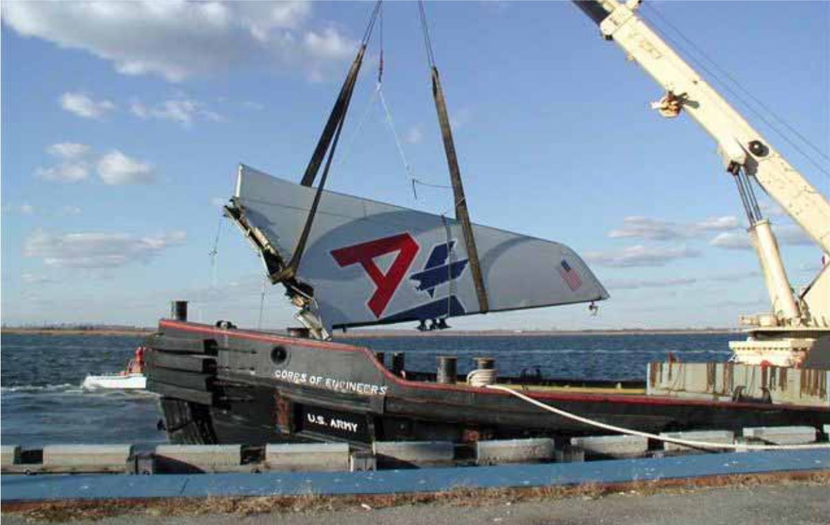 The recovered vertical stabiliser of American Airlines Flight 587 being lifted by a crane beside a US Army Corps of Engineers vessel.
