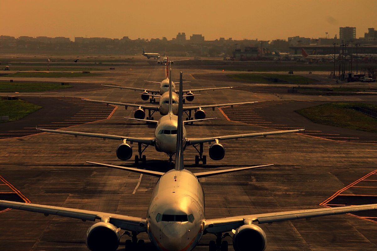 Several airliners lined up one behind another on a taxiway, waiting to take off.