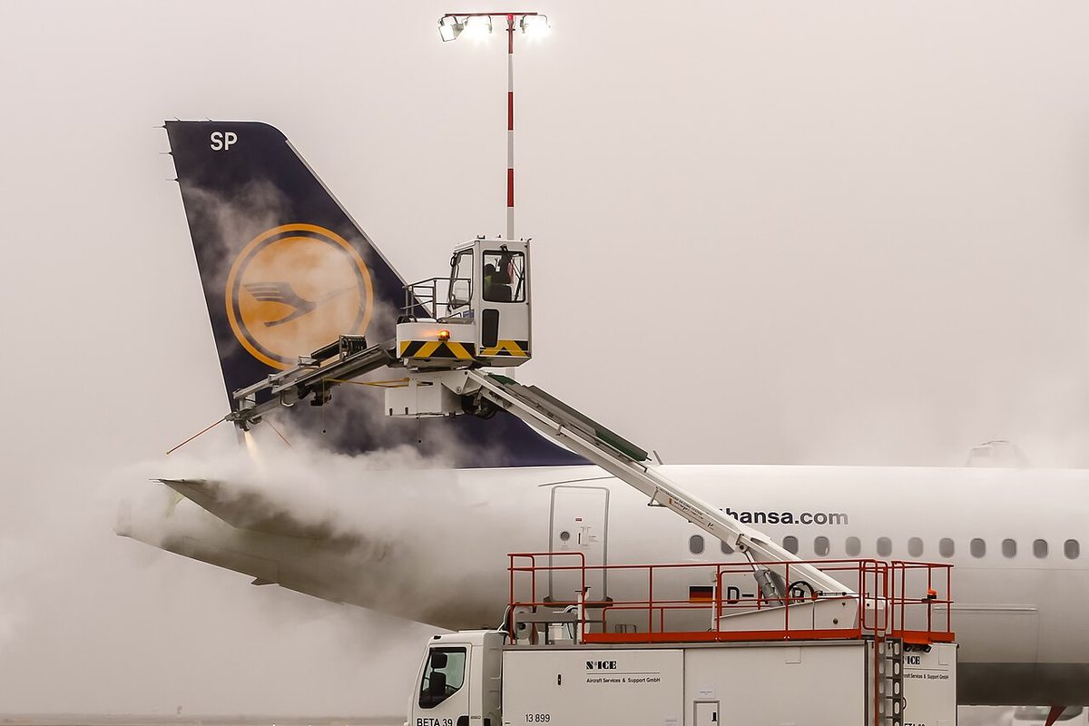 A de-icing vehicle spraying heated fluid over the wing and fuselage of an Airbus A321.