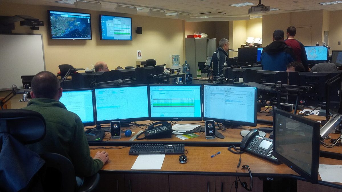 Operators working at consoles with screens and maps in a rescue coordination centre.