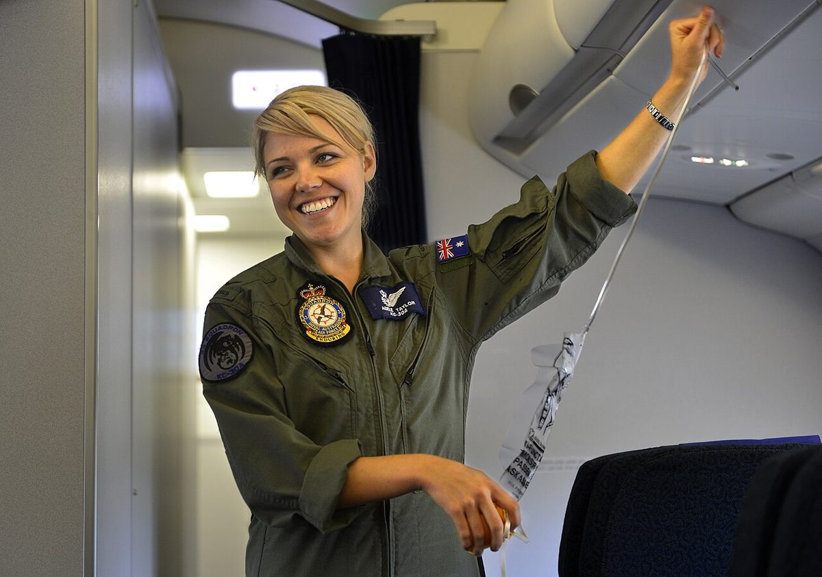 A Royal Australian Air Force crew member in uniform giving a safety briefing on board a KC-30A aircraft.