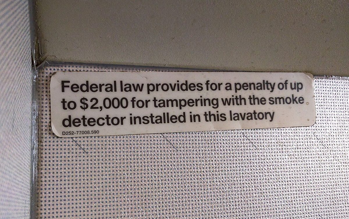 A placard on a lavatory wall: Federal law provides for a penalty of up to 2,000 dollars for tampering with the smoke detector installed in this lavatory.