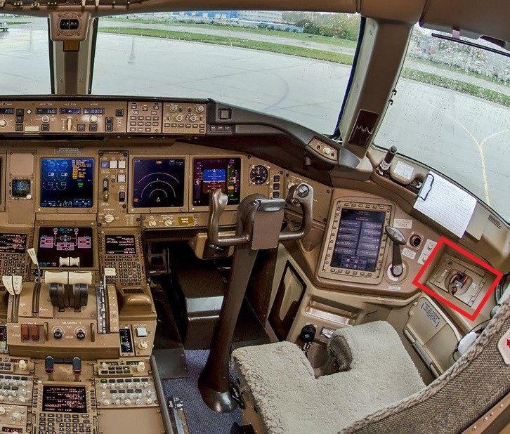 Boeing 777 flight deck with the stowage box of the first officer's quick-donning oxygen mask highlighted beside the seat.