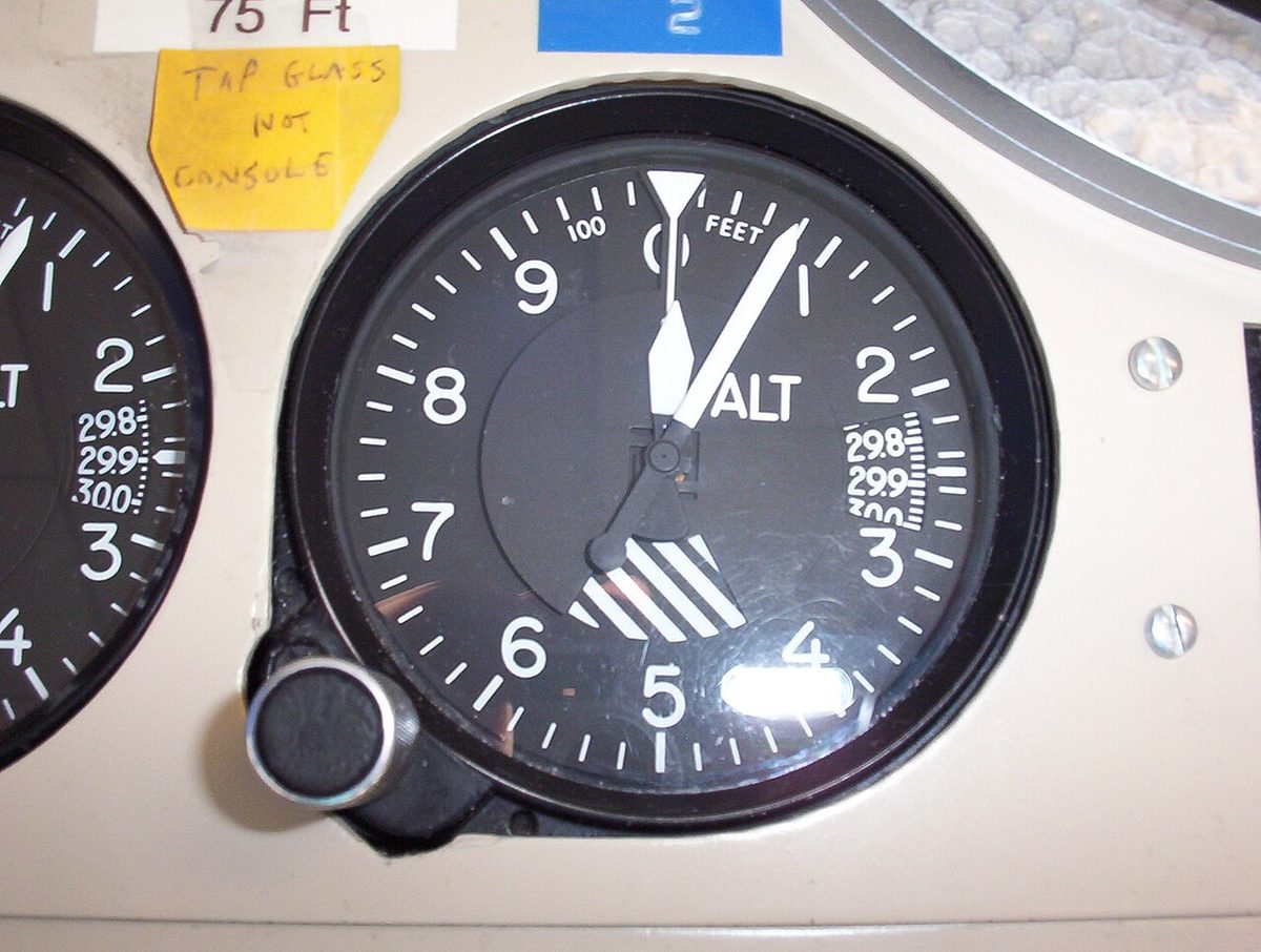 A sensitive altimeter set in a console, its pointers reading about 75 ft, with a subscale window graduated 29.8 to 30.0 on the right.