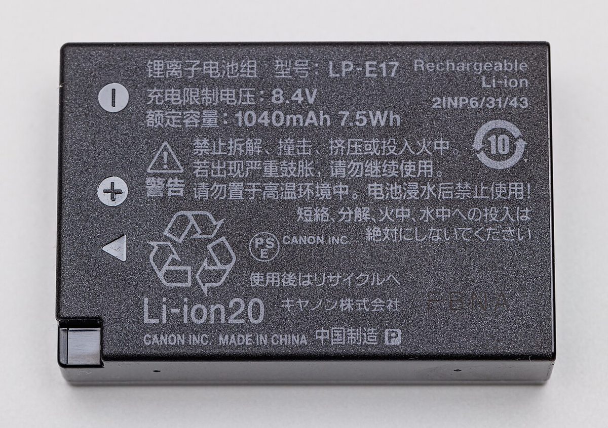 Close-up of a dark rechargeable battery pack whose printed label reads Li-ion, 8.4 V, 1040 mAh and 7.5 Wh, with metal terminals at one corner.