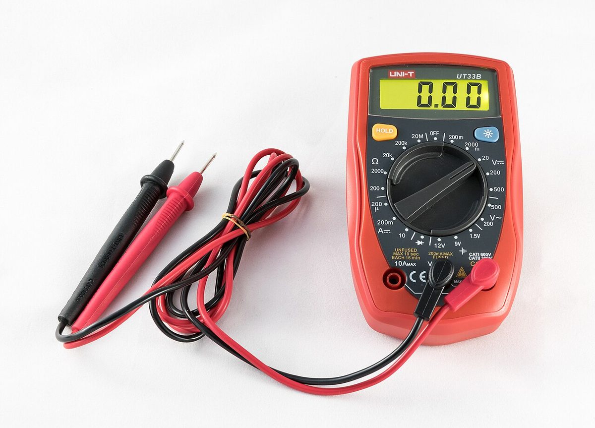 A handheld digital multimeter with a display and a rotary range selector.