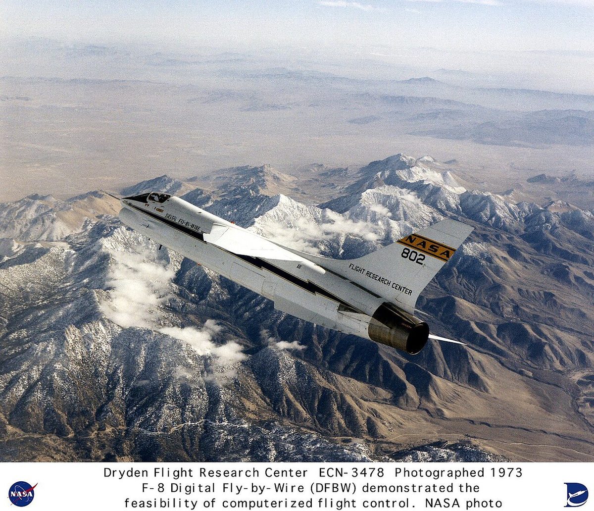 NASA's F-8 Crusader digital fly-by-wire research aircraft in flight above snow-capped mountains.