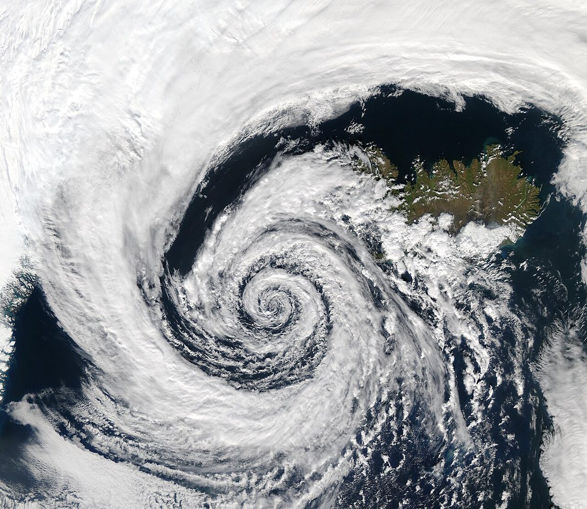 Satellite view of a large spiral of cloud wound around the centre of a low-pressure system over the ocean near Iceland.