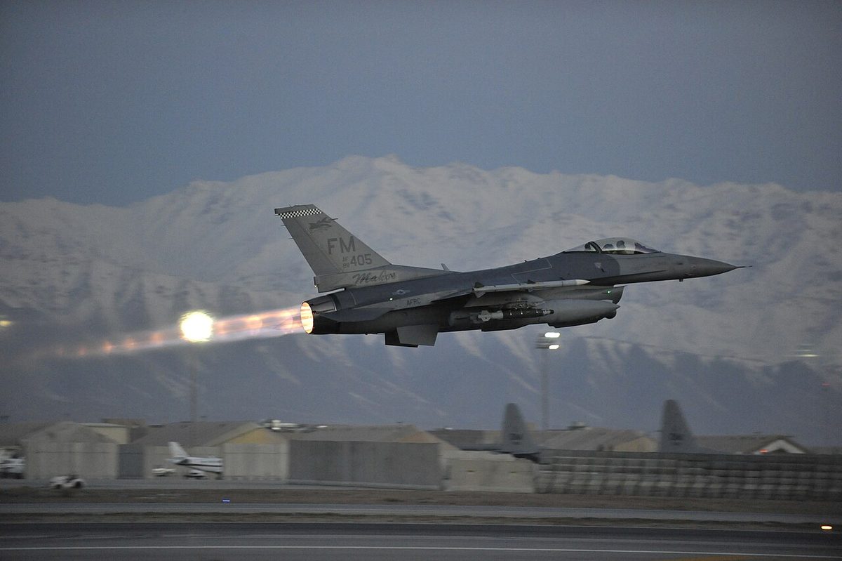 A fighter aircraft with a long, bright flame streaming from its engine exhaust.
