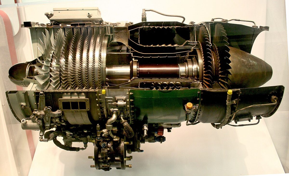 A sectioned jet engine on display, with rows of compressor blades visible along its length.