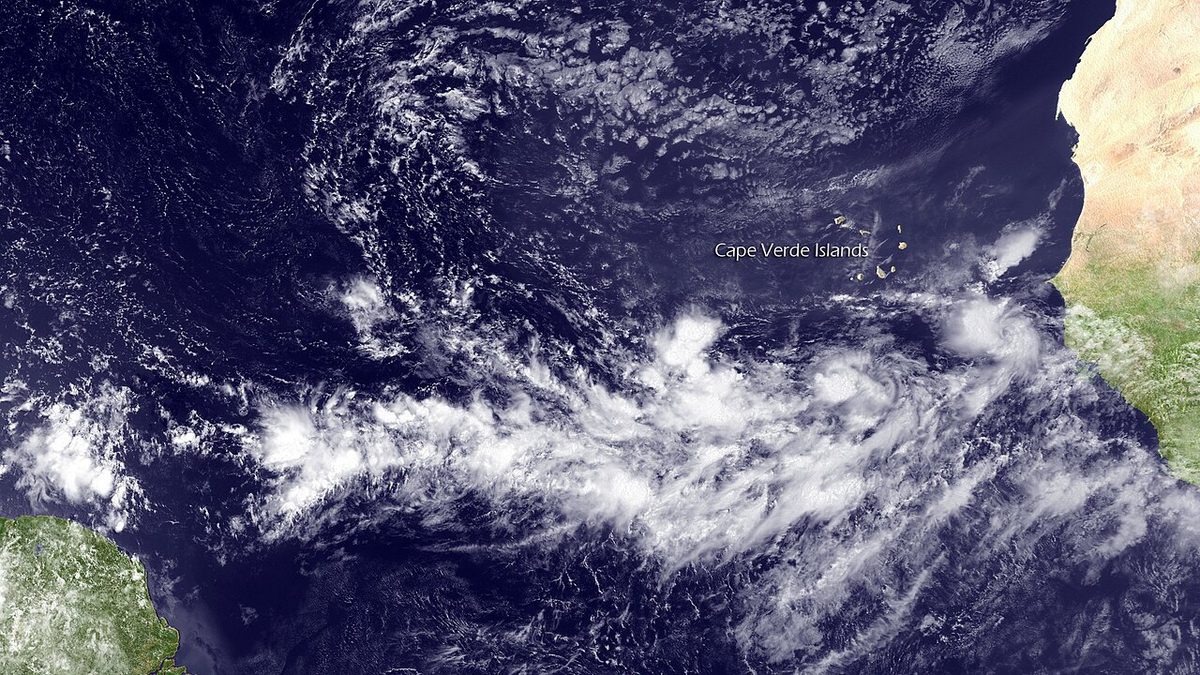 Satellite view of dark blue ocean off the west coast of Africa, crossed by a broad band of white cloud clusters.