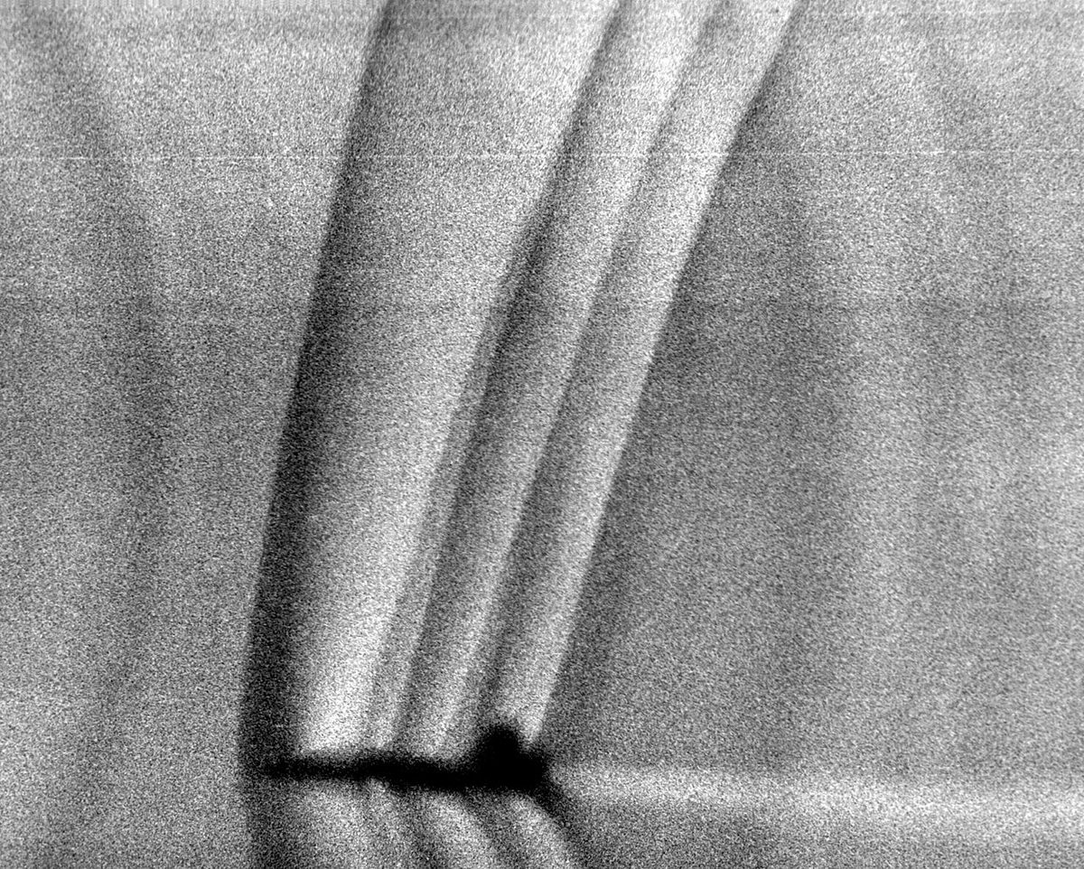 Schlieren image of a T-38 jet trainer in supersonic flight showing shock waves spreading from the nose, wings and tail.