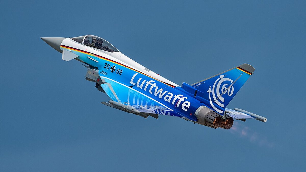 A German Air Force Eurofighter Typhoon climbing against a blue sky, painted blue with the word Luftwaffe on its side.