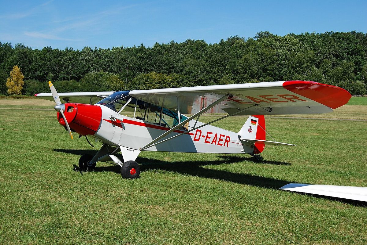 A small high-wing Piper Super Cub light aircraft with two main wheels at the front and a small wheel under the tail.