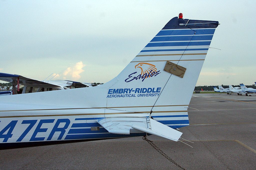 The tail of a parked light aircraft with a wooden gust lock clamped over the rudder and fin.