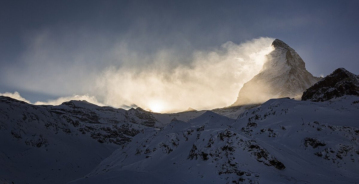 A mountain peak with a plume of cloud streaming from its summit on one side.