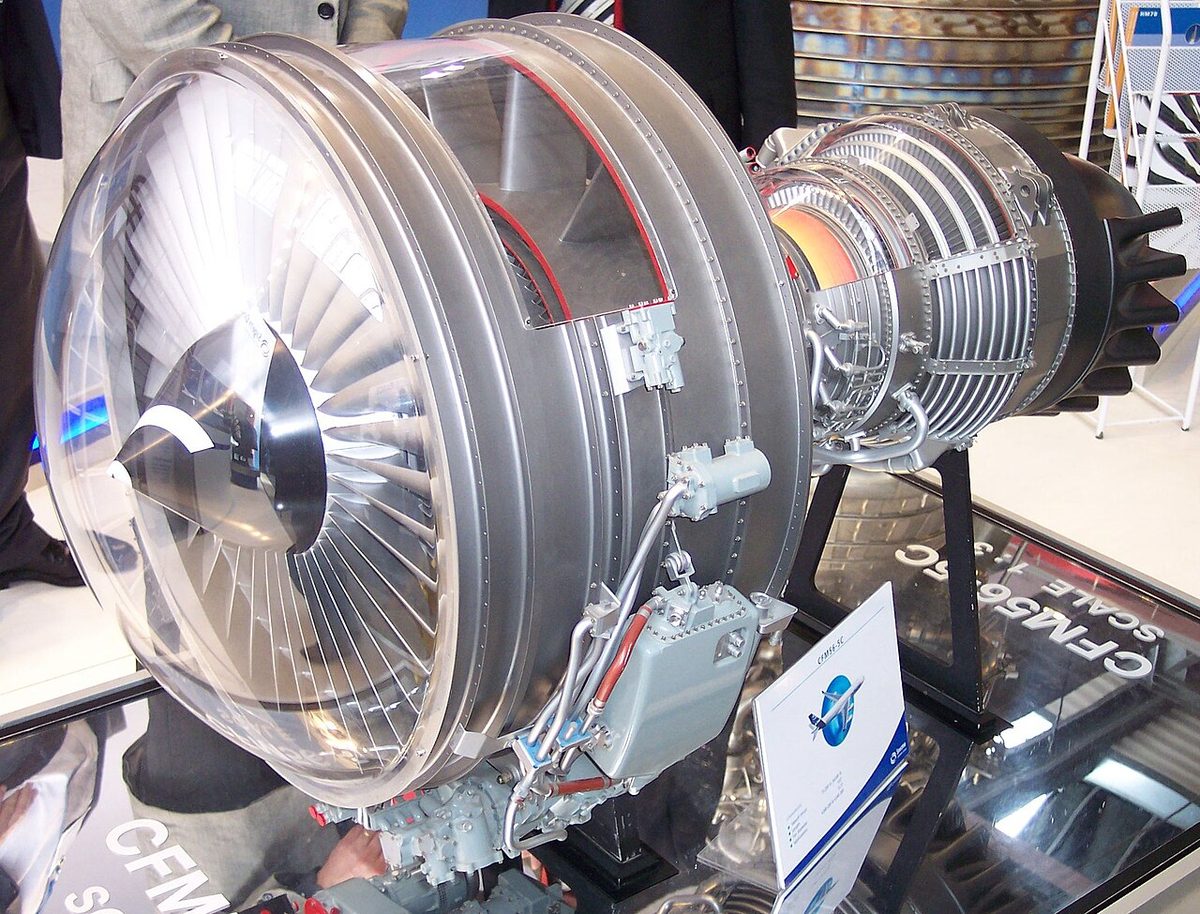 A cutaway model of a jet engine on a display stand, showing a large front fan and the compressor and turbine stages of the core behind it.