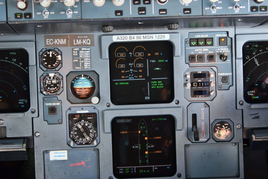 The flight deck of an Airbus A320, with display screens in front of each seat and the centre pedestal between the seats.