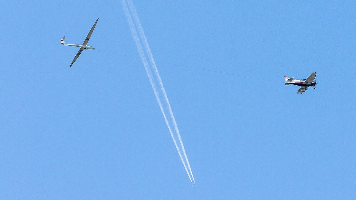 A glider on a tow rope behind a single-engine light aeroplane.