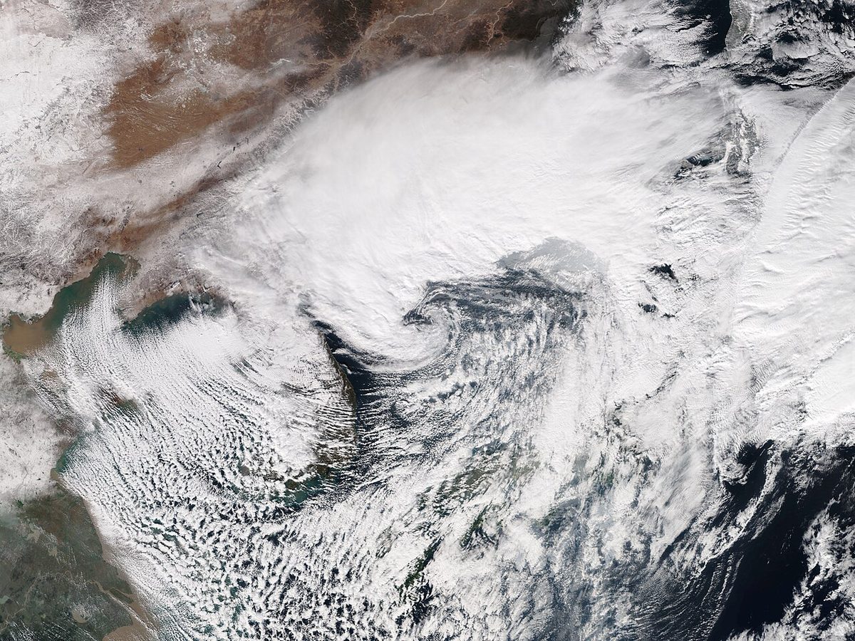 Satellite view of a small, tightly wound spiral of cloud over a cold northern sea.