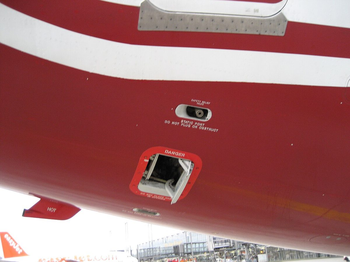Red-painted underside of a fuselage with an open rectangular valve outlined in red and marked DANGER, and a small oval vent above it.