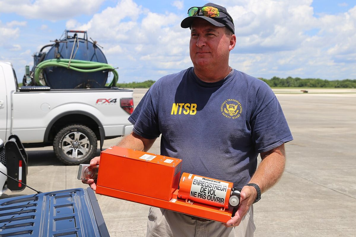 An accident investigator holding up a flight data recorder recovered after an accident.