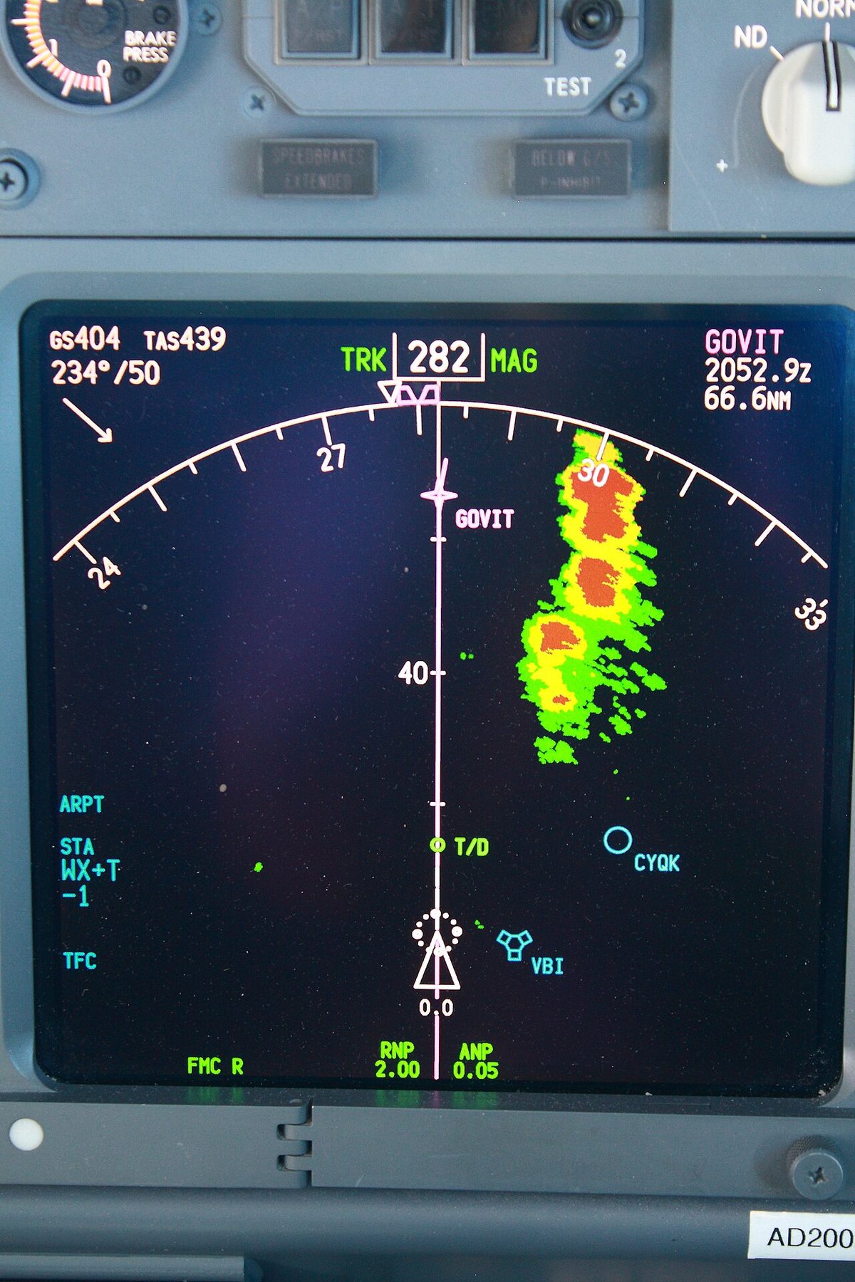 Navigation display with a magenta track line and, to the right, a patch of radar returns in green, yellow and red.