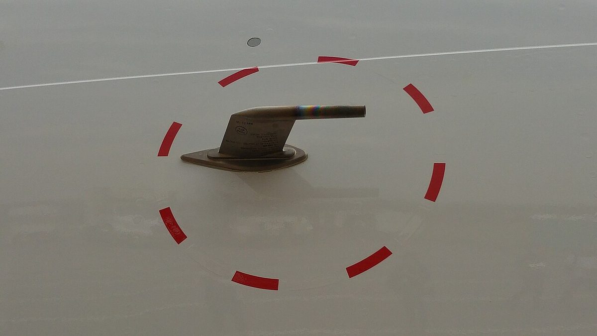 Small pitot probe sticking out from the gray skin of an aircraft nose, circled with a red dashed line.