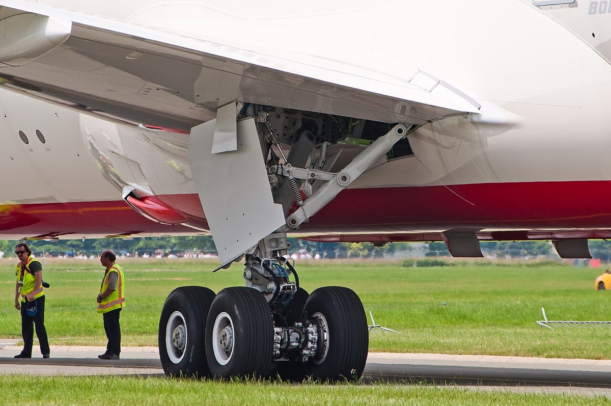The main landing gear of an Air India Boeing 787 on the ground: a four-wheel bogie under a single leg, with a side brace and gear doors above.