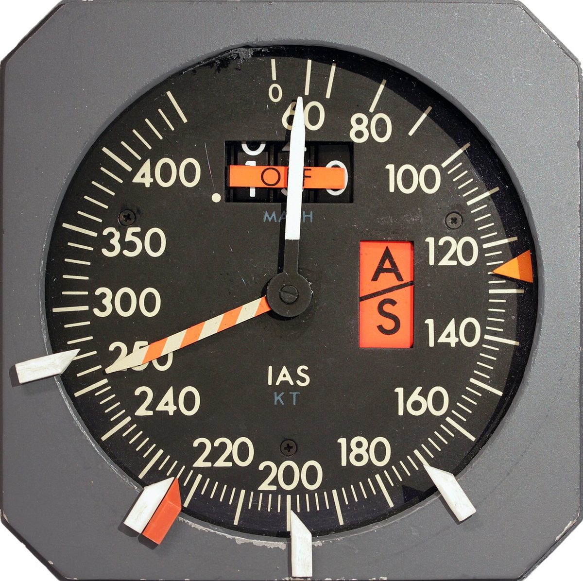 A round airspeed indicator from a McDonnell Douglas DC-10, with a red and white striped pointer and several movable white markers around the edge of the dial.