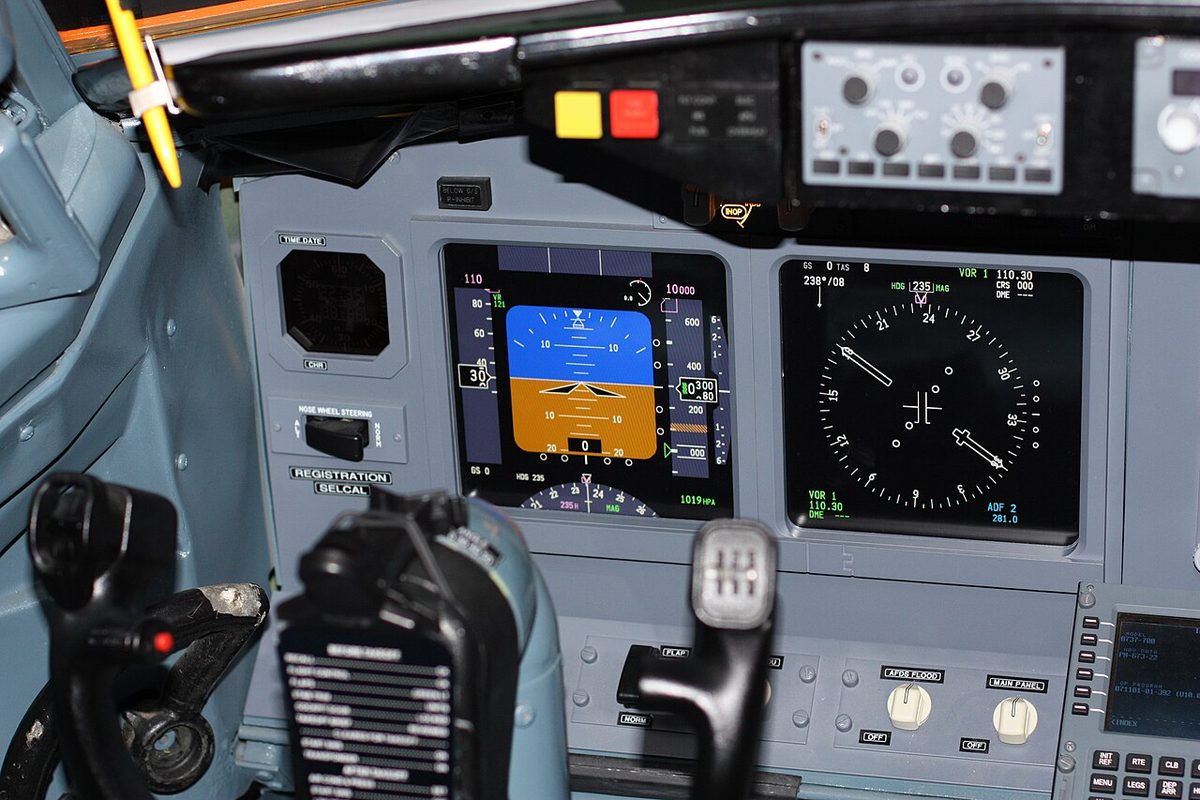 Close view of a Boeing 737 captain's panel: a control column in front of a blue and brown attitude display and a round navigation display.