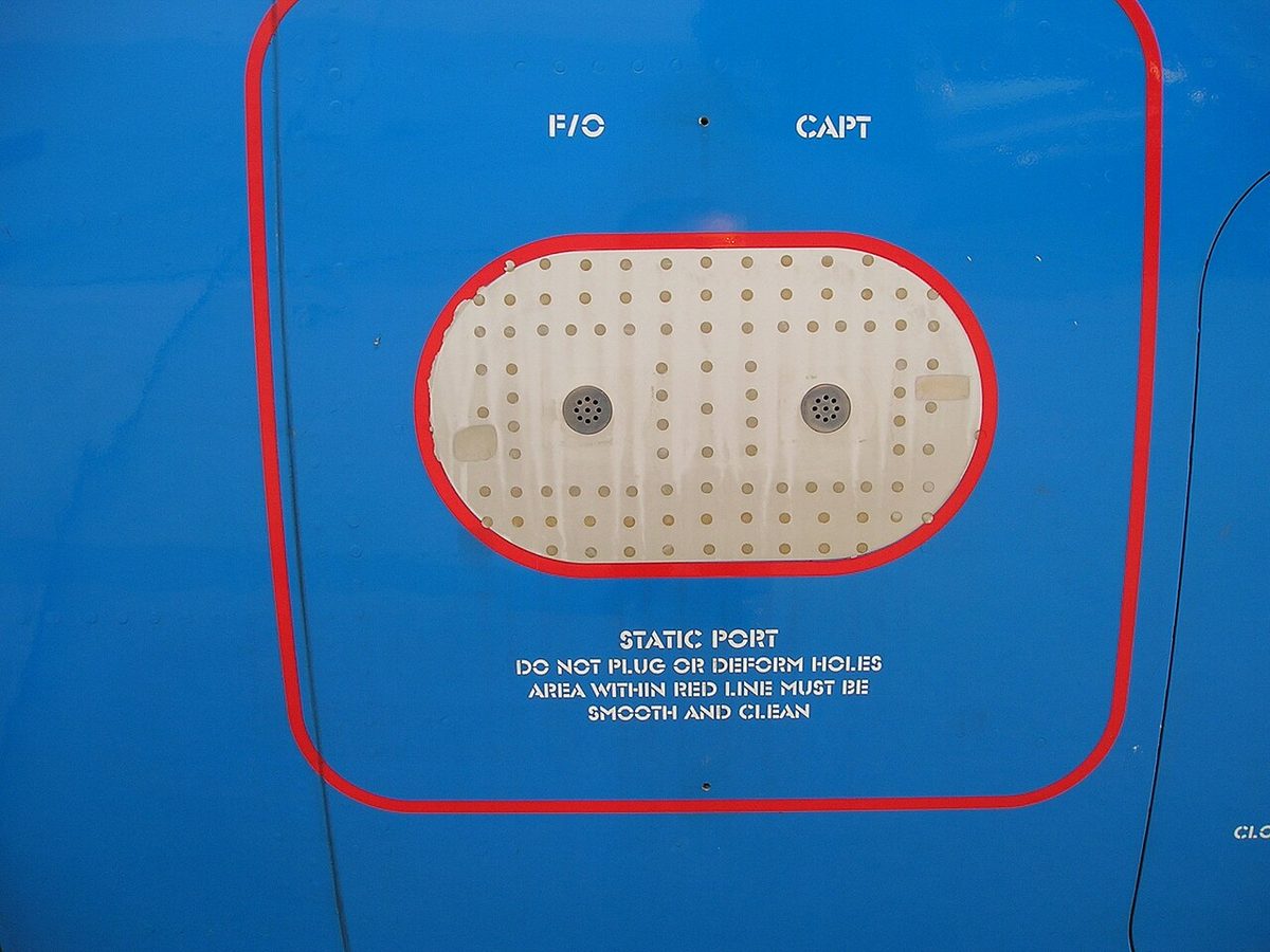A blue fuselage panel with a perforated plate holding two small static holes labeled F/O and CAPT, inside a red outline with the warning not to plug or deform the holes.