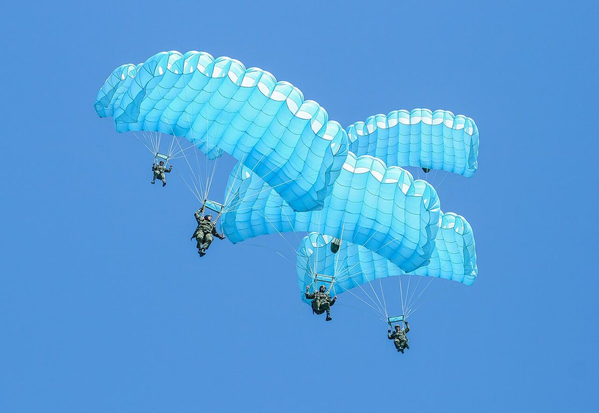 Parachutists descending under open canopies.