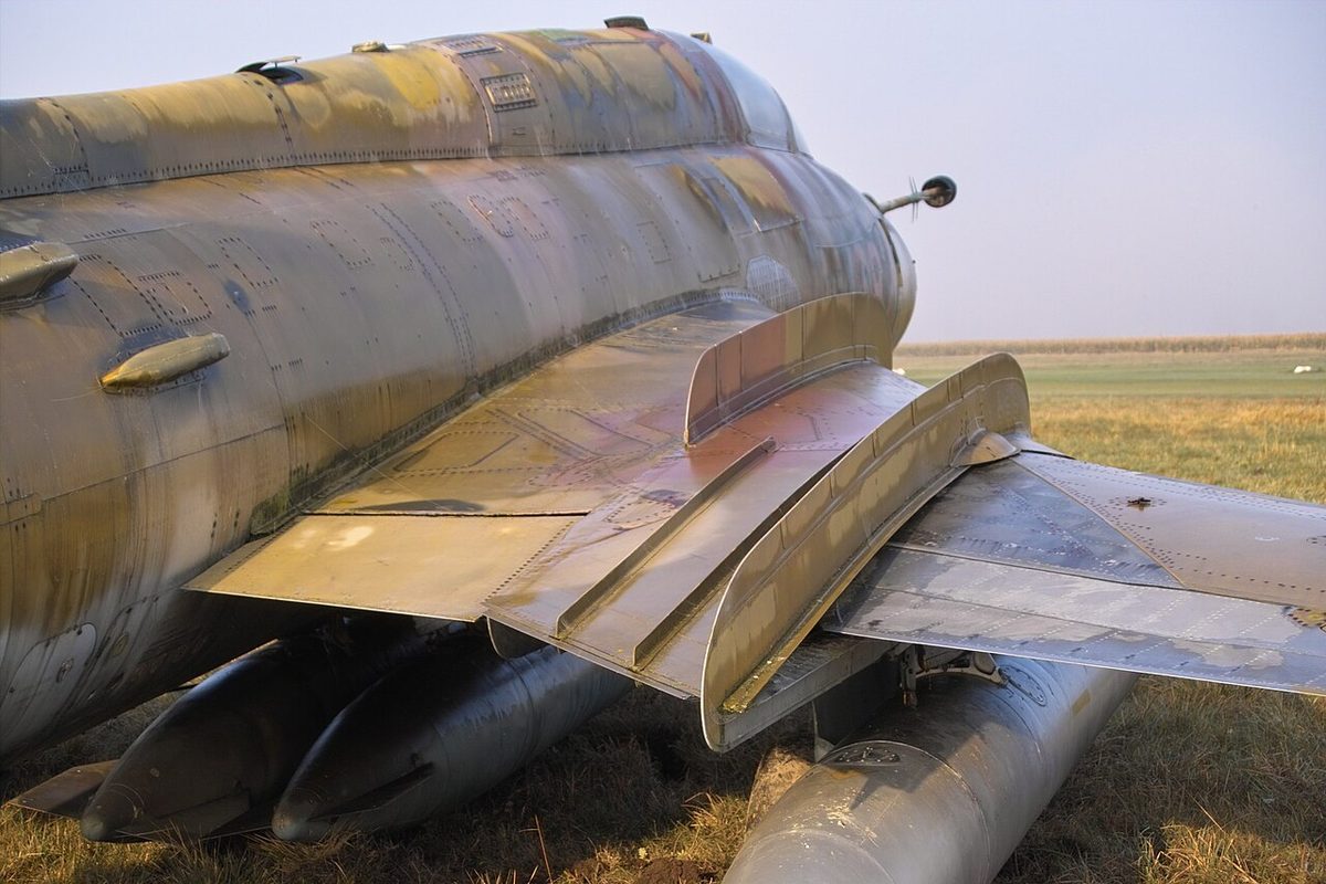The wing root of a Sukhoi Su-22 jet, with two tall plates standing upright on the upper surface of the wing, aligned with the airflow.