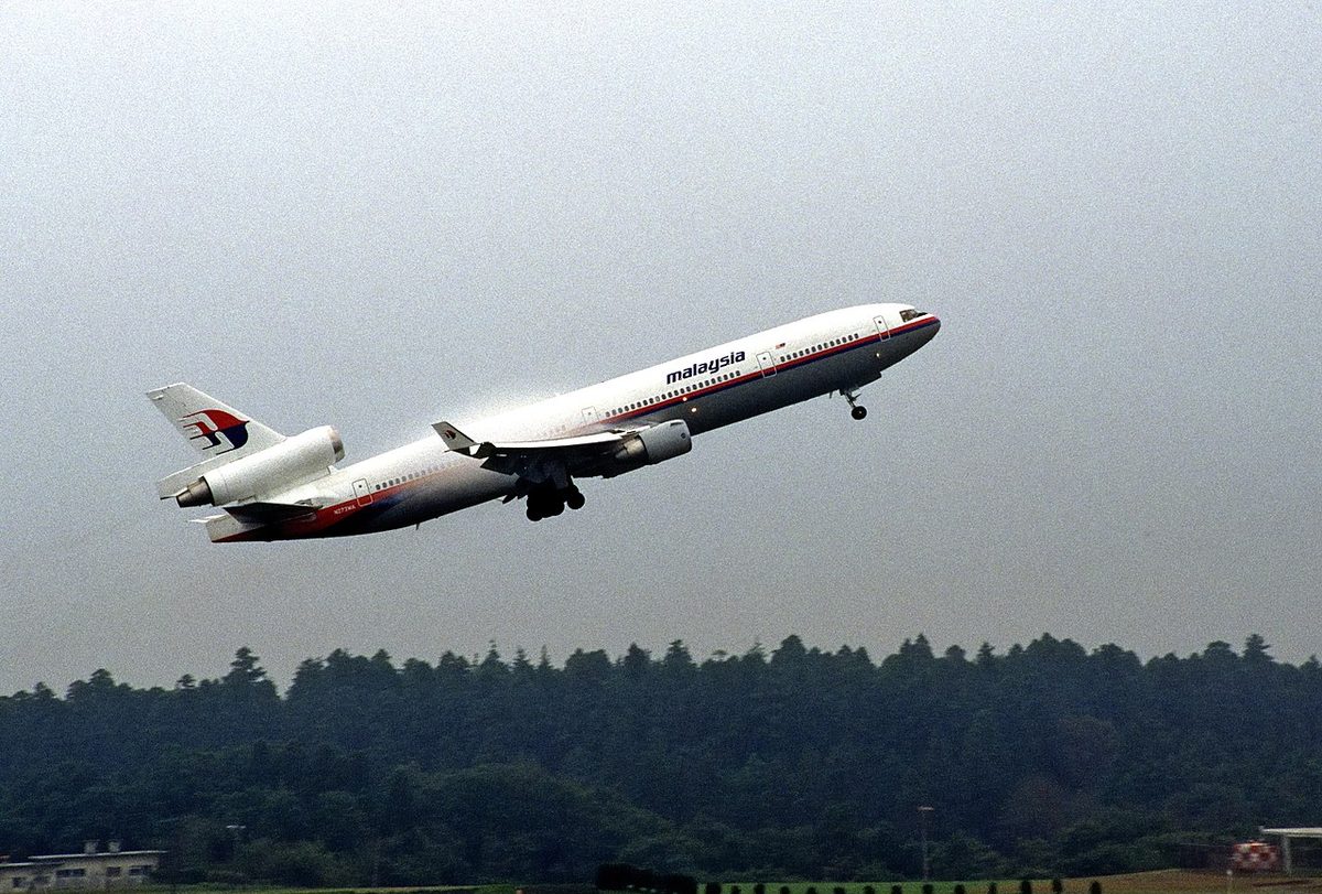A three-engined McDonnell Douglas MD-11 airliner in Malaysia Airlines livery during its take-off.