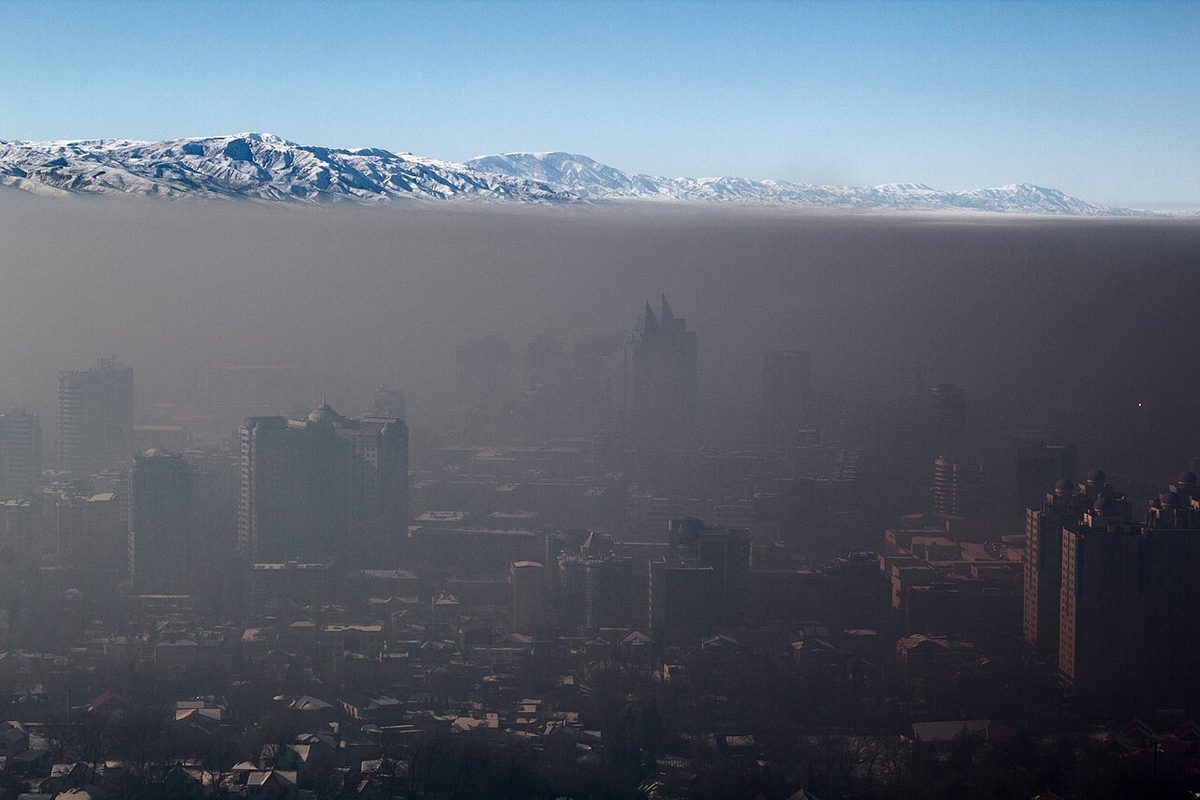 A city lying under a layer of smog, with clearer air above it.