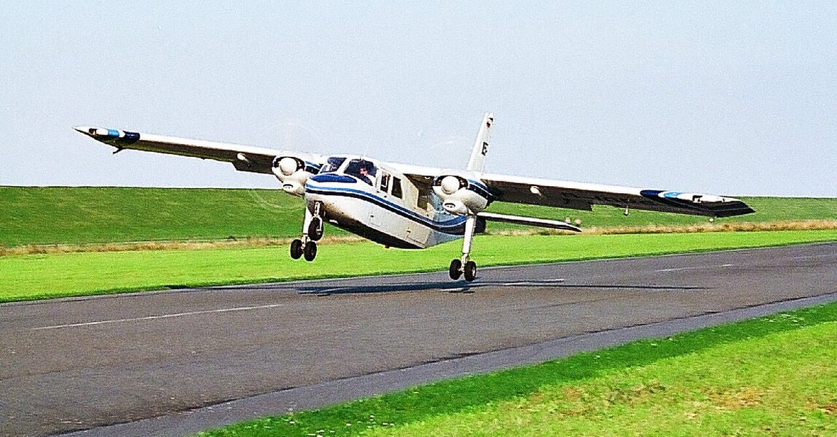 A Britten-Norman Islander, a small twin-engined aircraft, just above the runway in a crosswind landing, its nose pointed to one side of the runway direction.