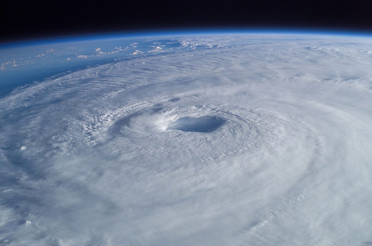 The eye of a hurricane seen from orbit, a clear circular centre ringed by a wall of bright cloud.