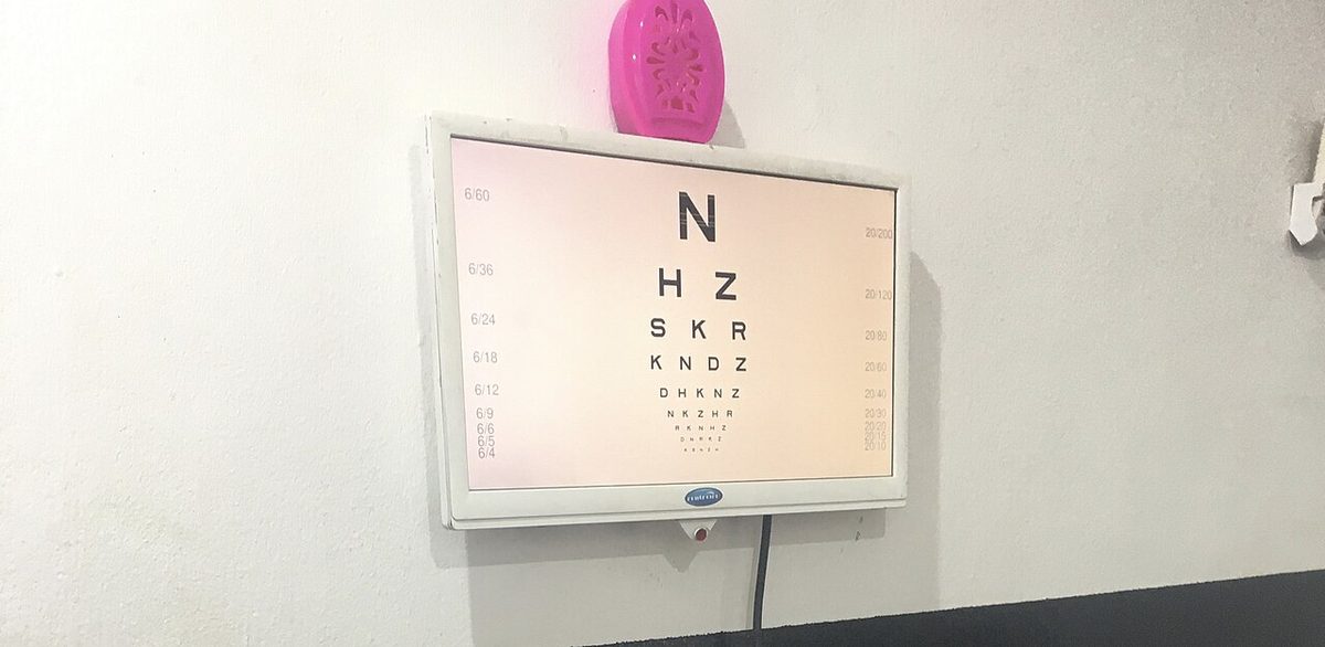 A lit eye chart with one large letter at the top and rows of smaller letters below, the vision fractions printed at each side.