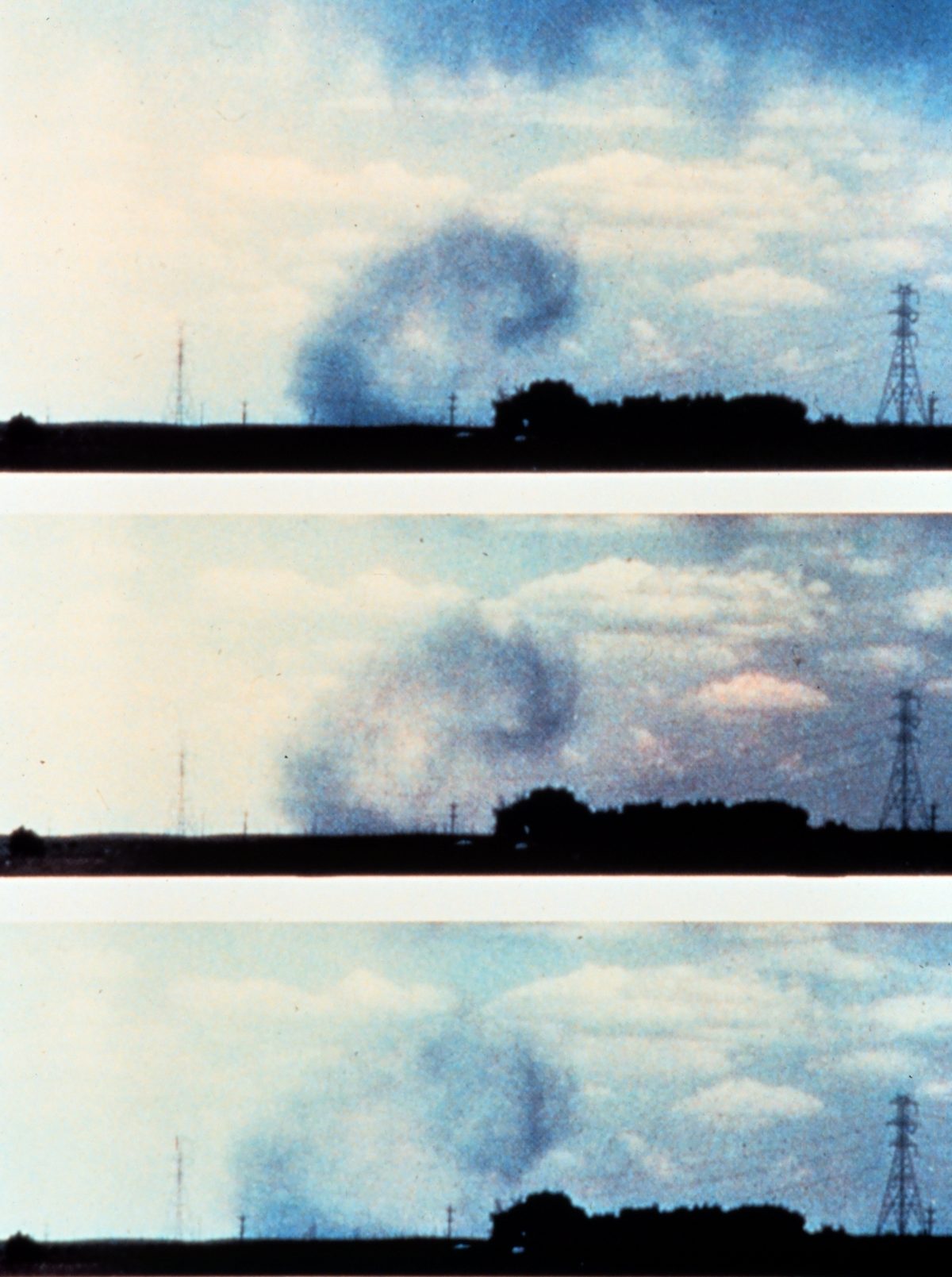 Three photographs taken in sequence of a microburst beneath a storm, its shaft of rain curling outward as it reaches the ground beside a line of power pylons.