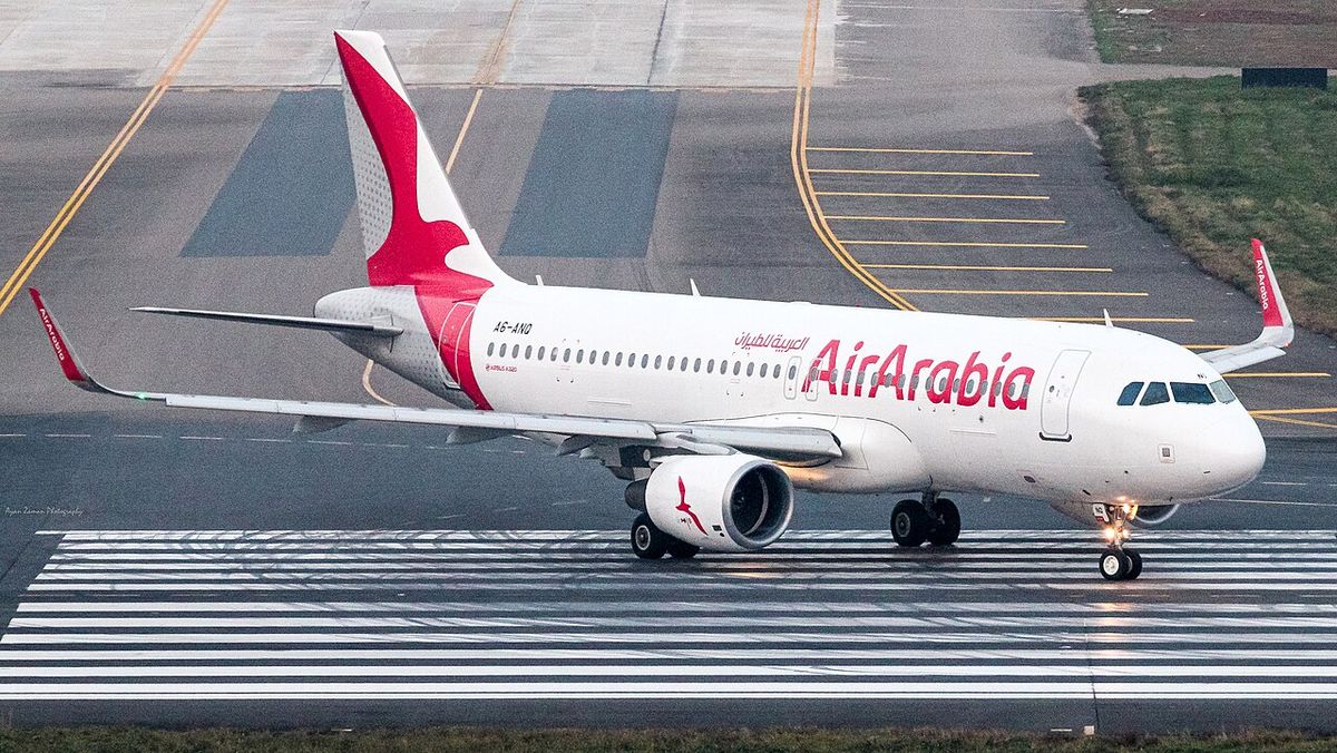 An Air Arabia Airbus A320 in white livery with the red bird on the tail, taxiing on a runway.