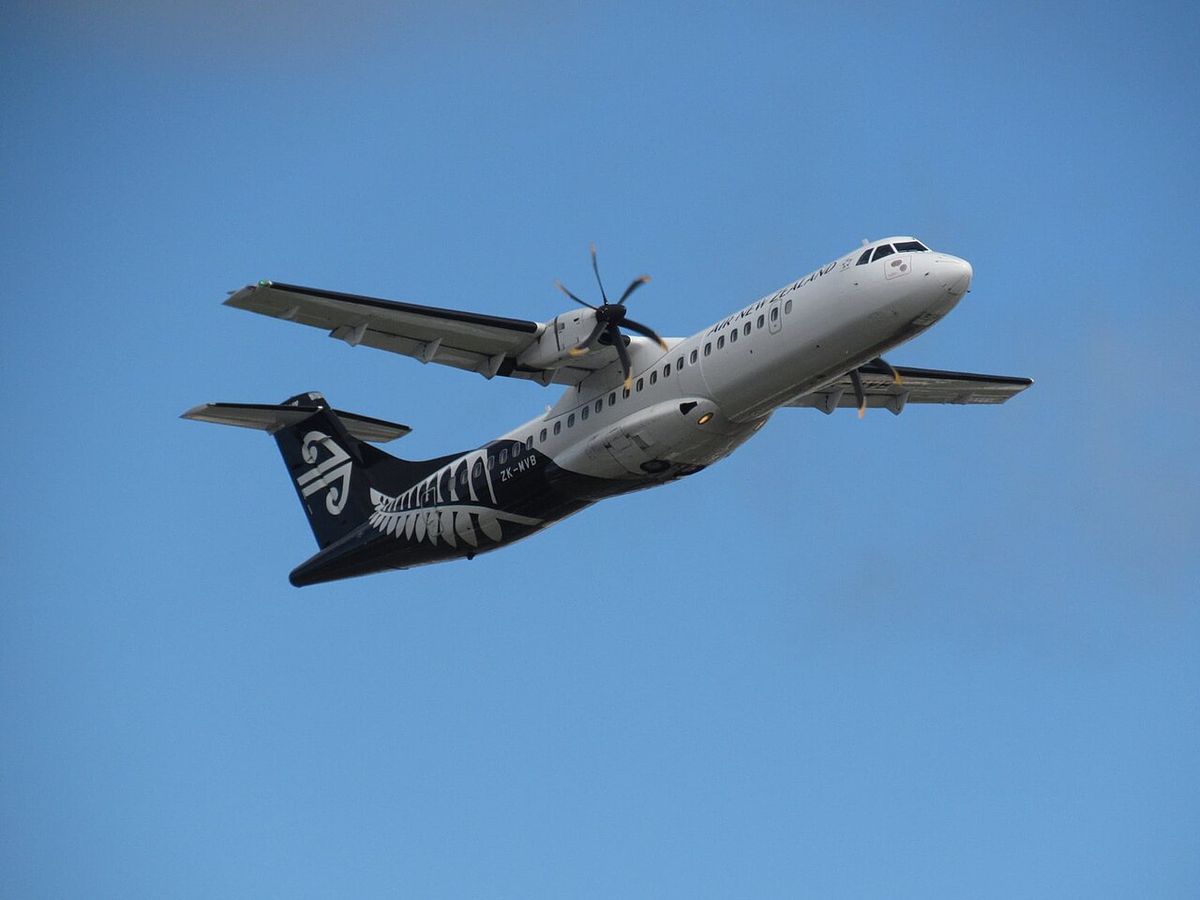 A white Air New Zealand ATR 72-600 turboprop with a black tail and silver fern, in flight against a blue sky.