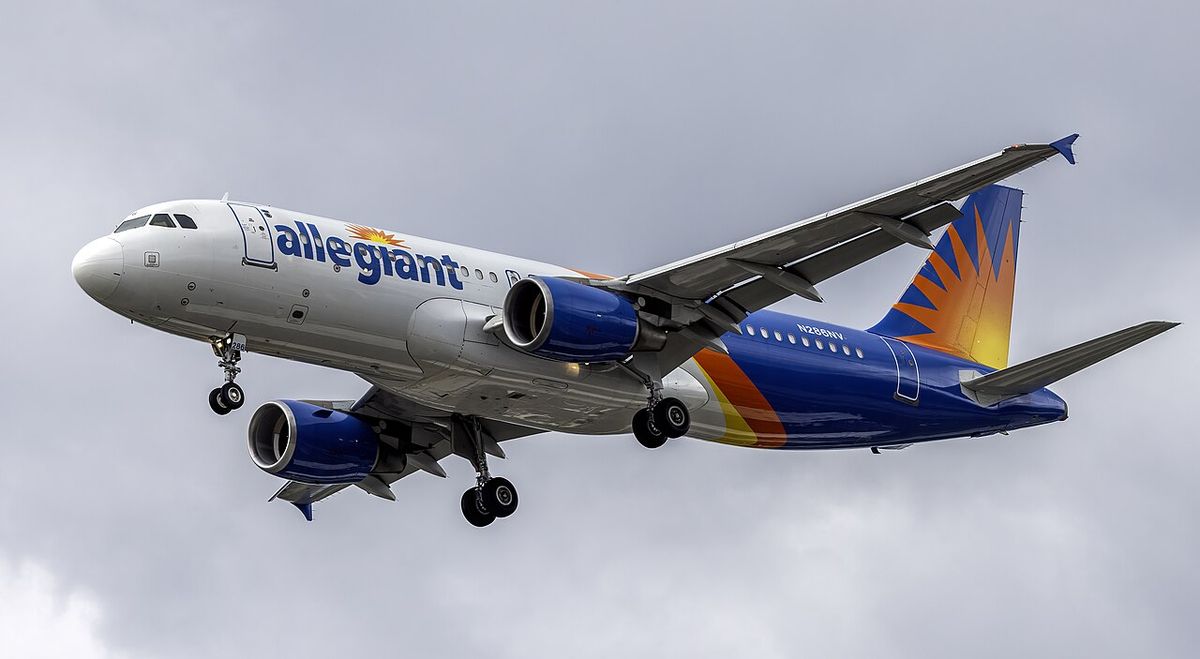 An Allegiant Air Airbus A320 in white, blue and orange livery with a sunburst tail, landing gear down on approach.