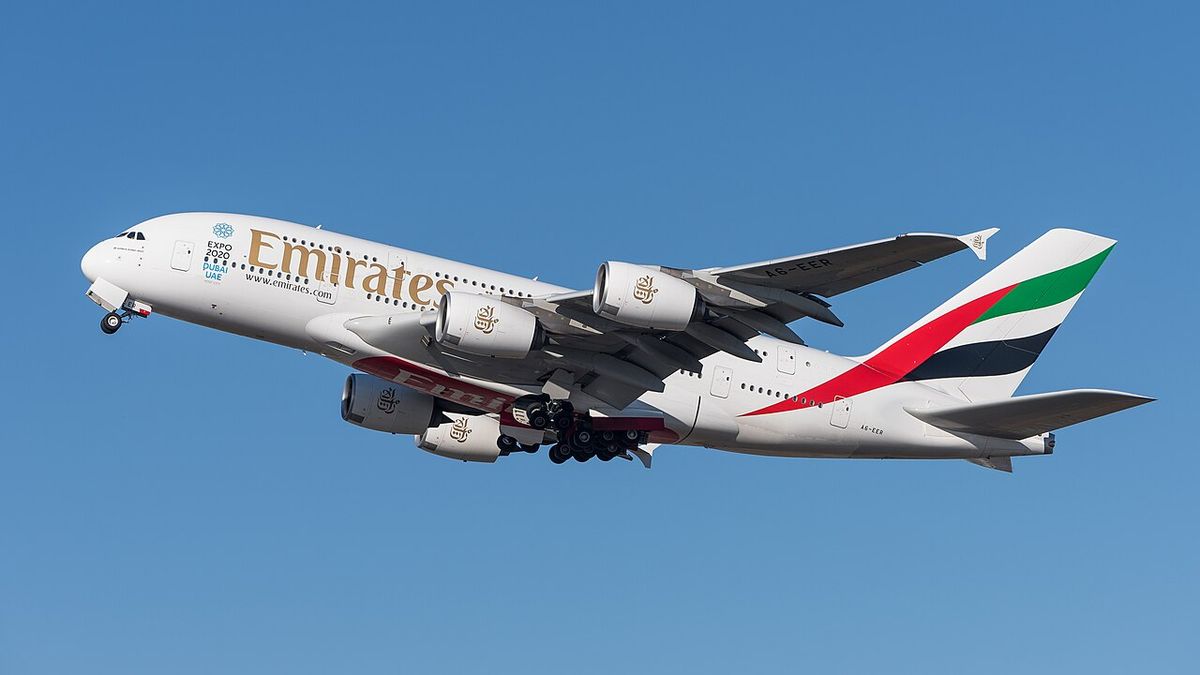 A white Emirates Airbus A380 with red, green and black tail stripes climbing away against a blue sky, gear retracting.