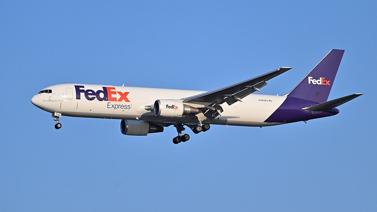 A white FedEx Express Boeing 767-300F freighter with a purple tail, landing gear down on final approach.