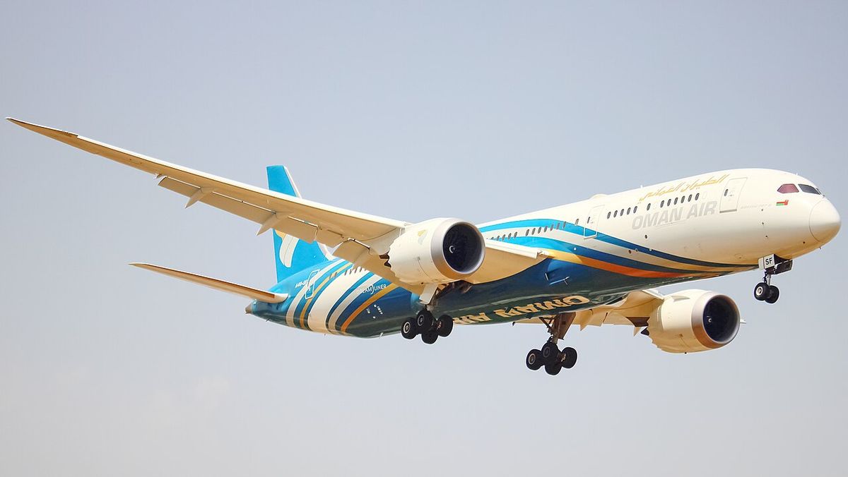 An Oman Air Boeing 787-9 in white livery with teal and blue stripes and the tail logo, gear down on approach.