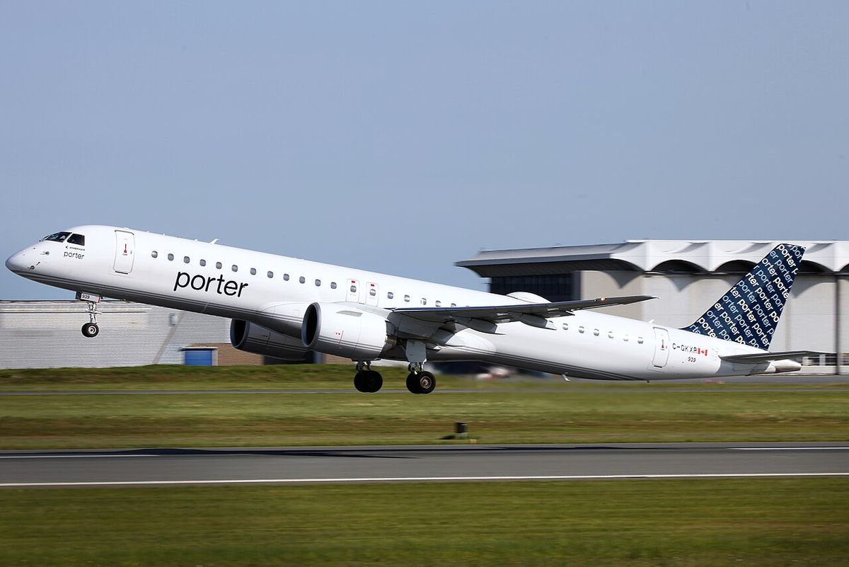 A white Porter Airlines Embraer E195-E2 with a navy-blue patterned tail, lifting off from a runway.