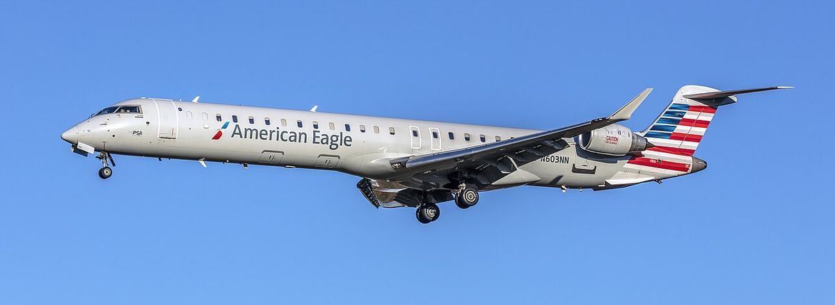 An American Eagle CRJ900 flown by PSA Airlines on final approach with its landing gear down.