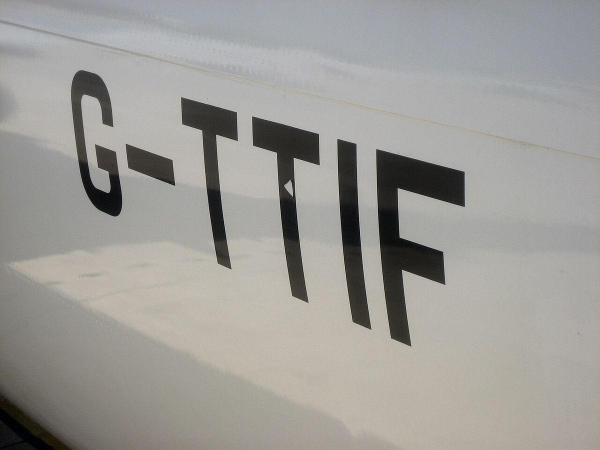 Large black letters G-TTIF painted on the white side of an aircraft.